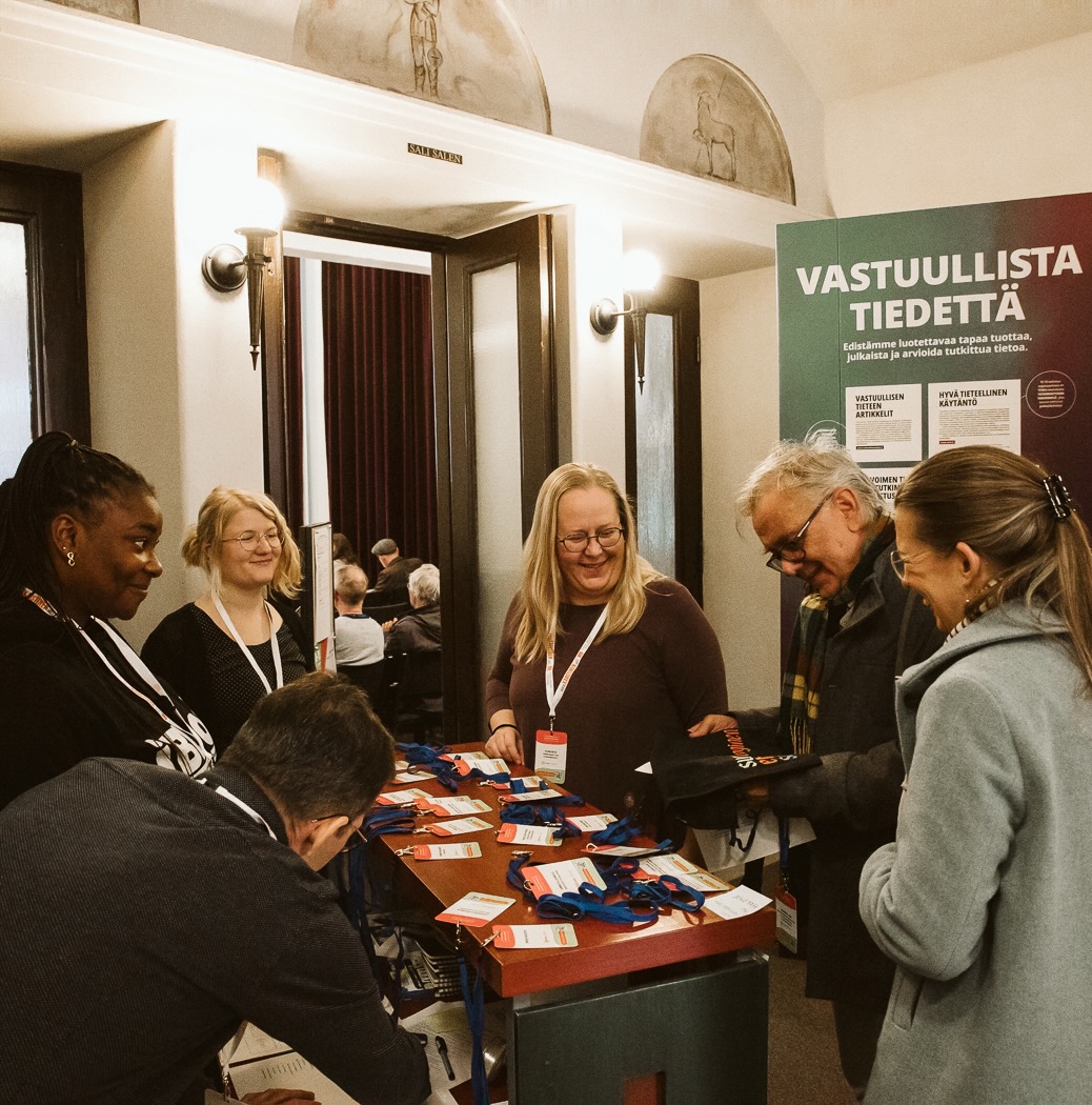 Henkilöitä kokoontuneena konferenssin rekisteröitymispisteen ympärille.